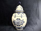 a blue and white vase with a lid sitting on a black background
