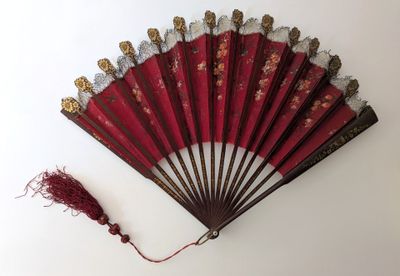 éventail chinois rouge orné de motifs dorés et d'un pompon rouge