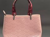 a pink handbag with a red handle on a grey background