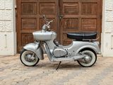 a silver motor scooter parked in front of a wooden door