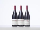 three bottles of red wine sitting on top of a white table