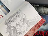 an open book sitting on top of a table next to a drawing
