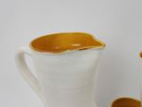 a white pitcher and a cup sitting next to each other