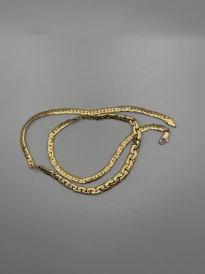 une paire de bracelets en or posés sur une surface grise