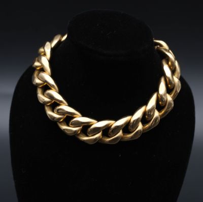 un collier en or posé sur un support à collier noir en forme de mannequin