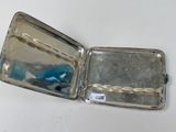 a small silver box with a blue object inside of it