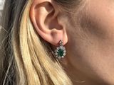a close up of a woman wearing a pair of green and white earrings