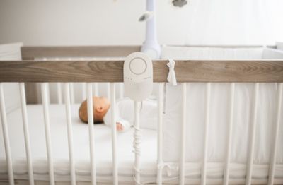 a baby laying in a crib next to a phone