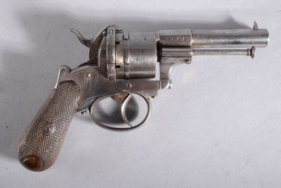 un revolver en argent avec une poignée en bois sur une surface blanche