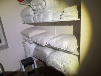 some white pillows are stacked on top of a shelf in a room