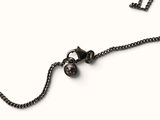 a black necklace with a skull on it on a white background