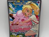 un gros plan sur une carte Pokémon représentant une fillette qui serre un cochon dans ses bras