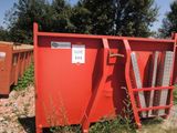 une benne rouge posée au milieu d'un champ