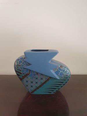 un vase bleu posé sur une table en bois, avec un mur blanc en arrière-plan