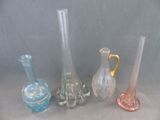 Plusieurs vases en verre de différentes couleurs sont alignés sur une surface grise