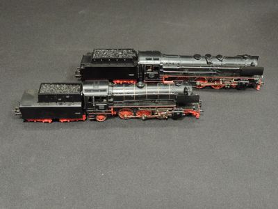two black and red trains sitting on a gray surface