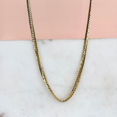 un collier à chaîne en or posé sur une surface en marbre