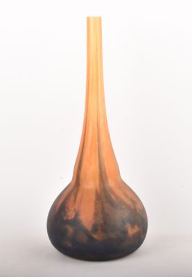 un vase noir et orange posé sur une surface blanche