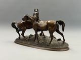 sculpture en bronze représentant deux chevaux sur un rocher, sur fond gris