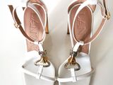 pair of white high heeled sandals with a gold chain on the ankle