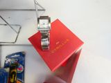 une montre posée sur une boîte rouge, à côté d'une paire de ciseaux