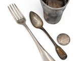 a silver cup with spoons and a fork next to it