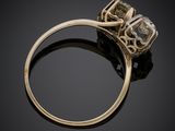 a close up of a gold ring with a green diamond