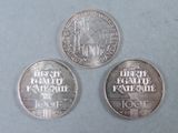 three silver coins sitting on top of a table next to each other