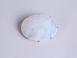 a close up of a white and blue broochle on a white surface