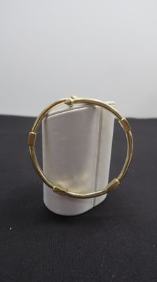 gros plan d'un bracelet en or sur une surface noire