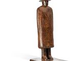 wooden statue of a man with a hat and coat on a wooden base