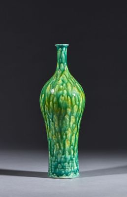 un vase vert posé sur une table sur fond noir