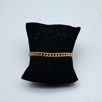 un oreiller noir sur lequel est posé un bracelet à chaîne dorée