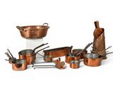 a lot of copper pots and pans on the table