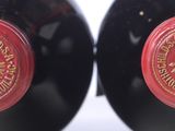 two bottles of red wine sitting next to each other on top of a table