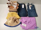 Plusieurs paires de jeans, un chapeau, une chemise et une paire de sandales sont disposés sur une table