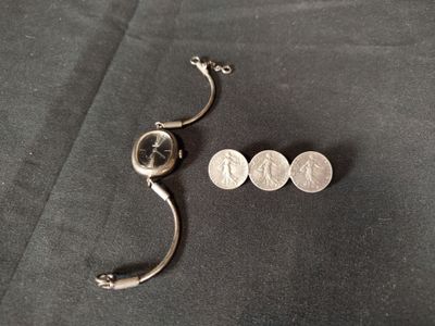 a small silver object on a black surface next to a coin