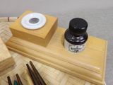 a small wooden box with a bottle of ink and chopsticks on it