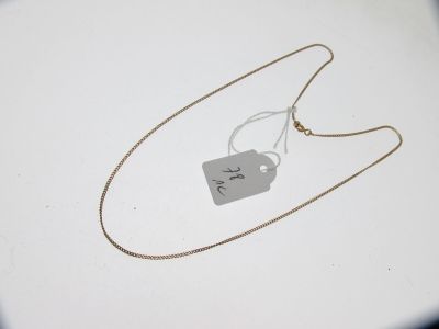 un collier en argent muni d'une médaille, posé sur une table