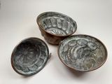 three small metal bowls sitting on top of a white table