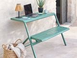 un ordinateur portable posé sur un banc vert à côté d'un panier