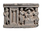 une sculpture en pierre représentant un groupe de personnes sur un socle