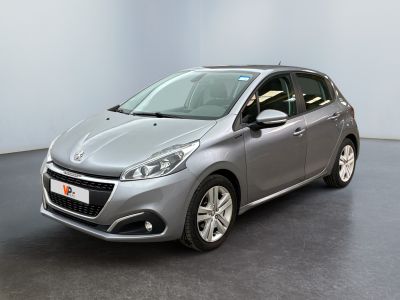 La voiture argentée est garée dans une pièce au sol noir.