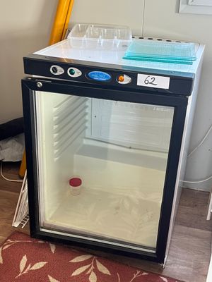un petit réfrigérateur avec une porte vitrée dans une pièce