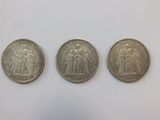 three different types of silver coins on a white surface