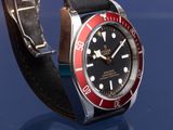 a red and black watch on a black leather strap