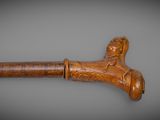 an old wooden cane with a carved head on a gray background