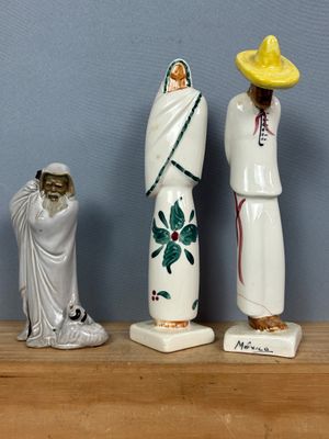 trois figurines représentant des personnes, disposées côte à côte sur une étagère