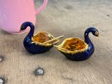 a blue and gold swan figurine next to a pink teapot