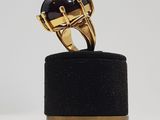 a gold ring with a black stone on a black stand